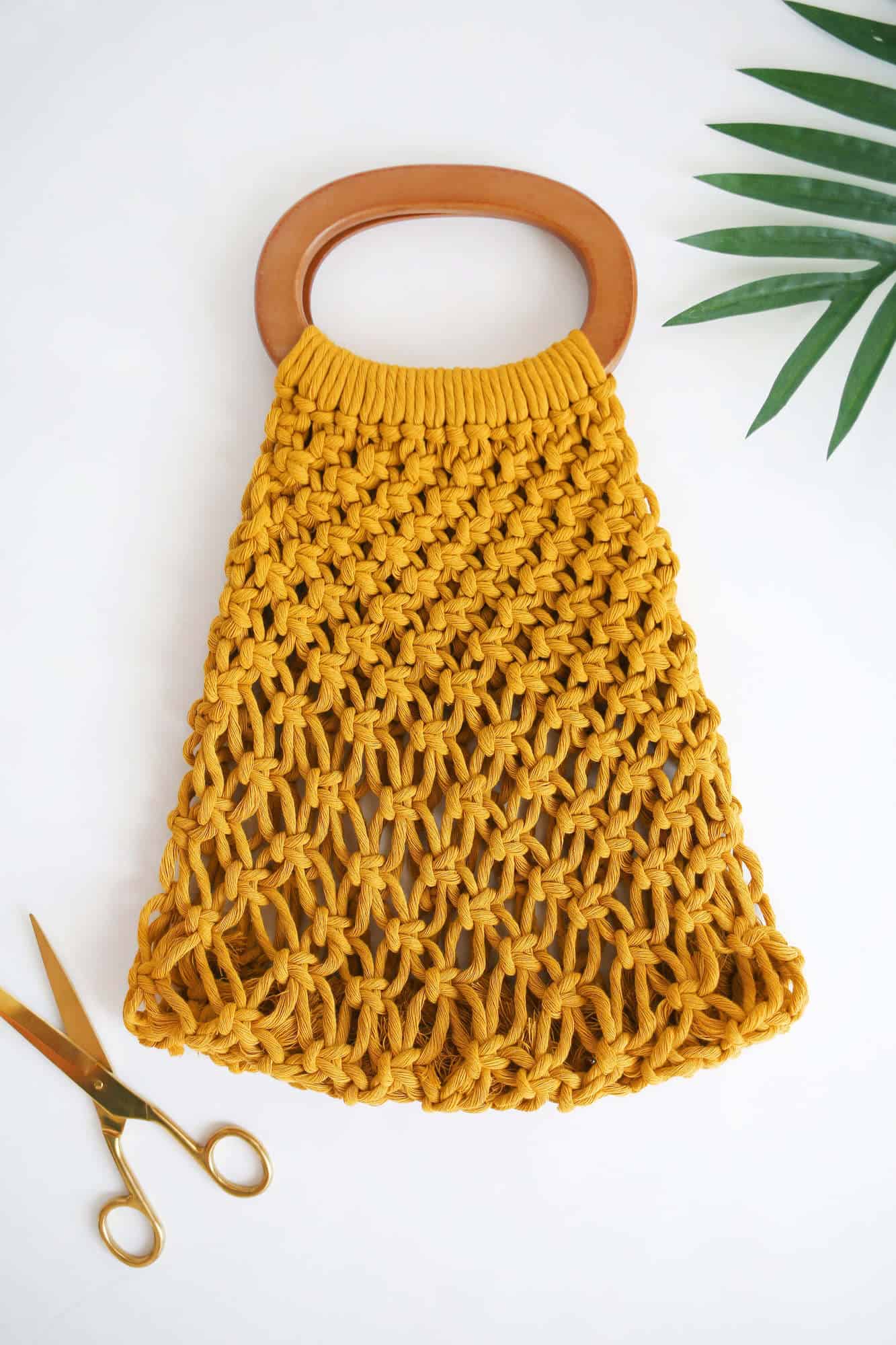 yellow macrame handbag with gold scissors next to it